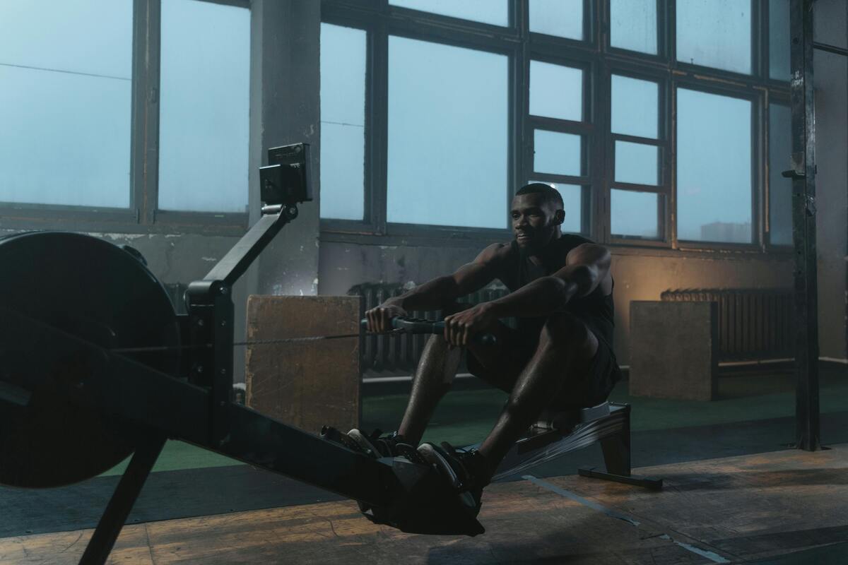 A long-distance shot of a man using a rower at a gym.