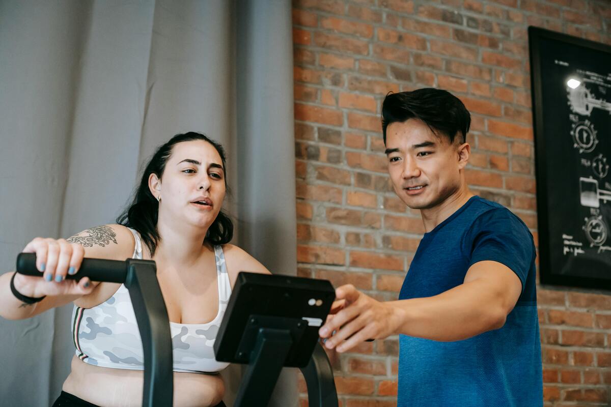 A woman working out with her trainer on a treadmill trying to lose weight.