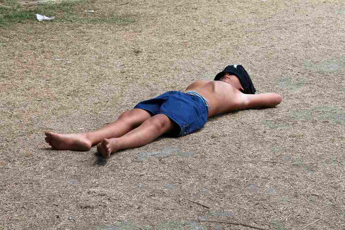 A person laying on a beach, unable to stay consistent with fitness goals.