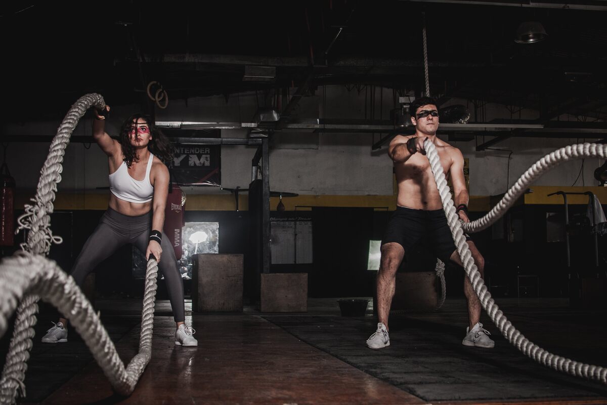 A man and a woman exercising with battle ropes.