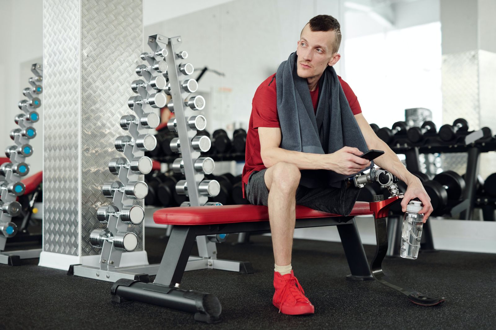 A man in a red shirt resting to recover after a gym exercise.