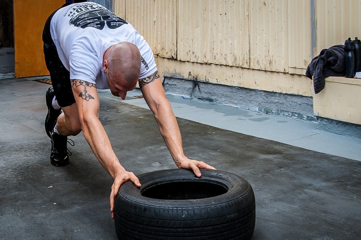 A person pushing a tyre as part of CrossFit to build strength and endurance.