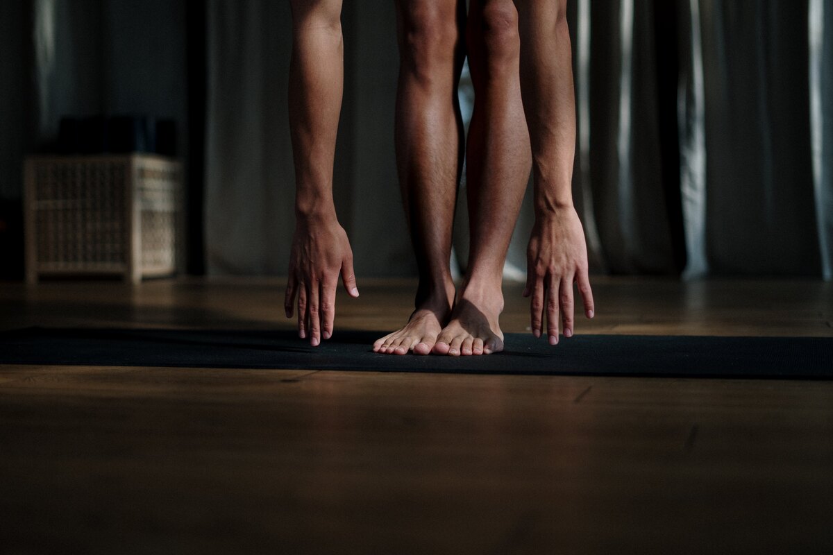 A person stretching and touching their toes to recover after training.