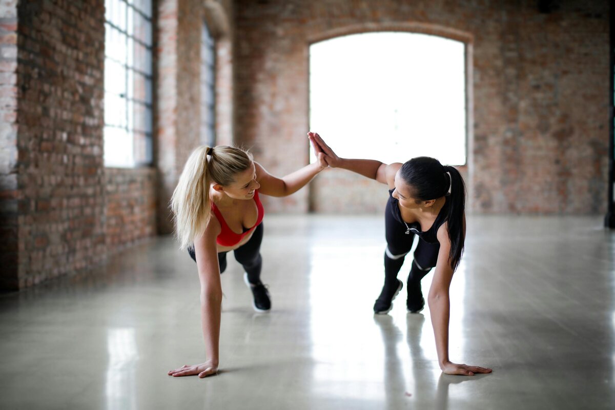 Two slender young women doing resistance training for women with their bodyweight.
